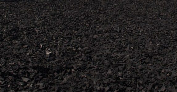 Clean edge of black rubber mulch against manicured lawn