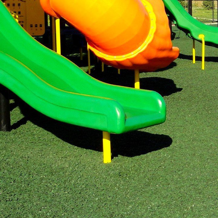 Green wavy slide landing on green rubber mulch