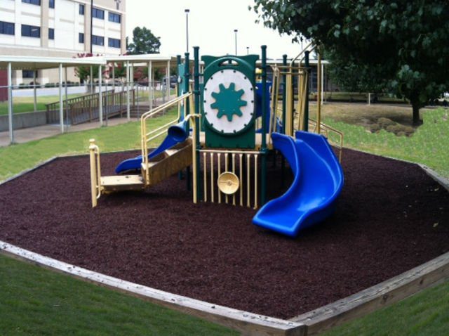 City park playground with blue slides on black rubber mulch safety surfacing