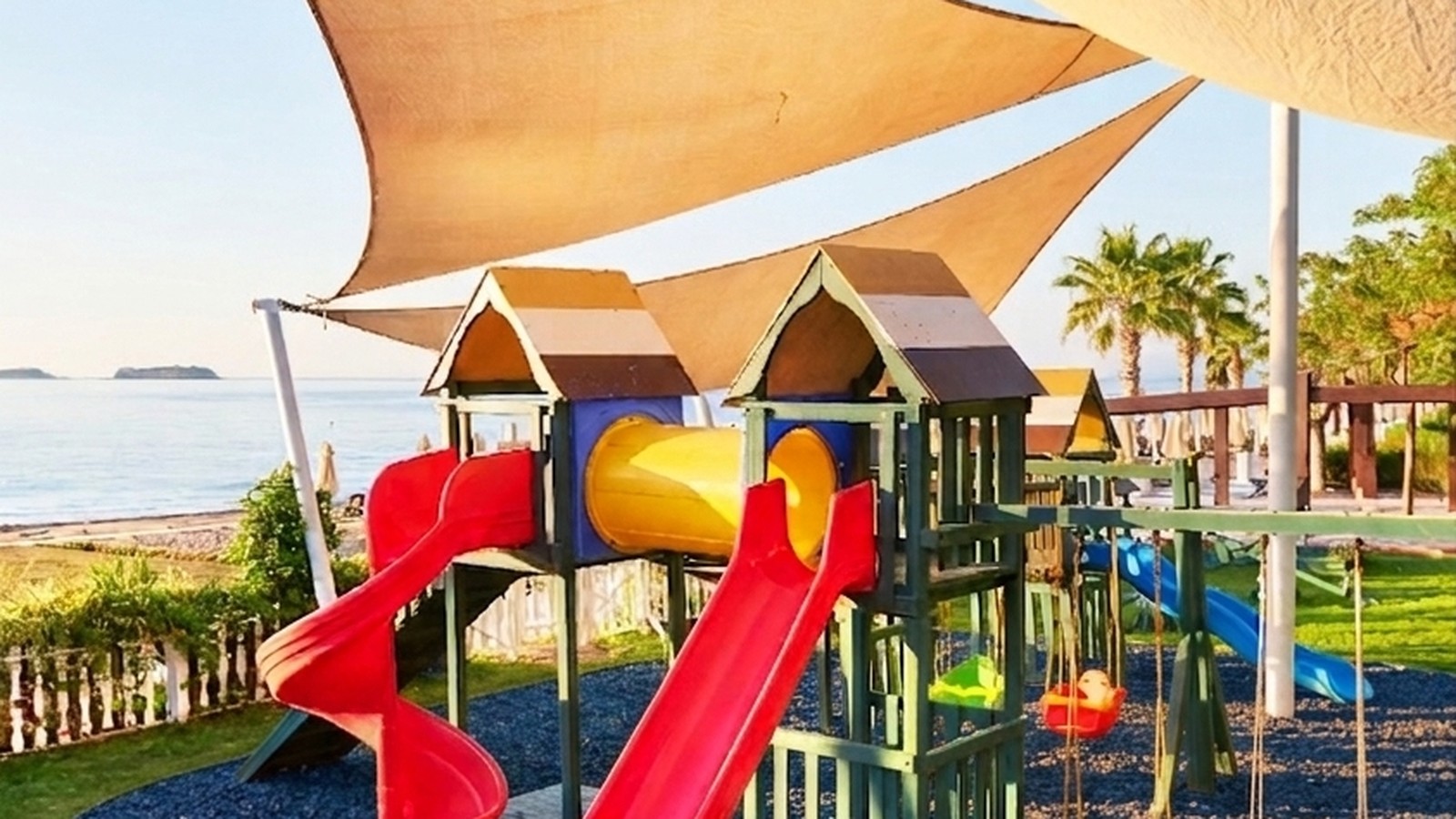 Shaded play structure with slides on a rubber mulch surface