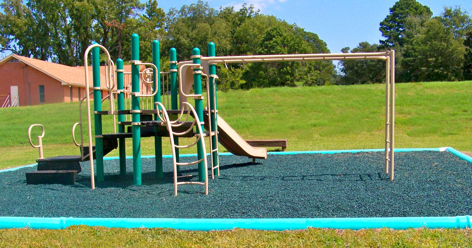 Park play structure with a slide and monkey bars on rubber mulch