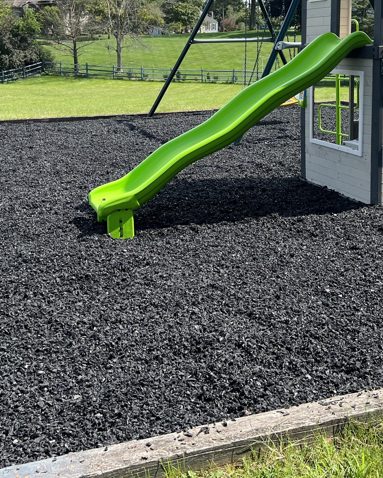 Slide landing on a rubber mulch play surface beside a lawn