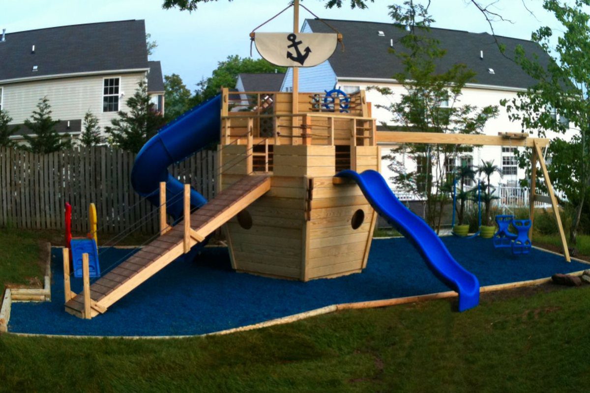 Wooden pirate-ship playset with a slide on rubber mulch