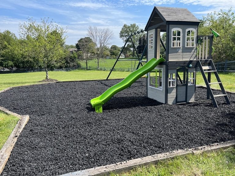 Unpainted natural rubber mulch under a backyard playset