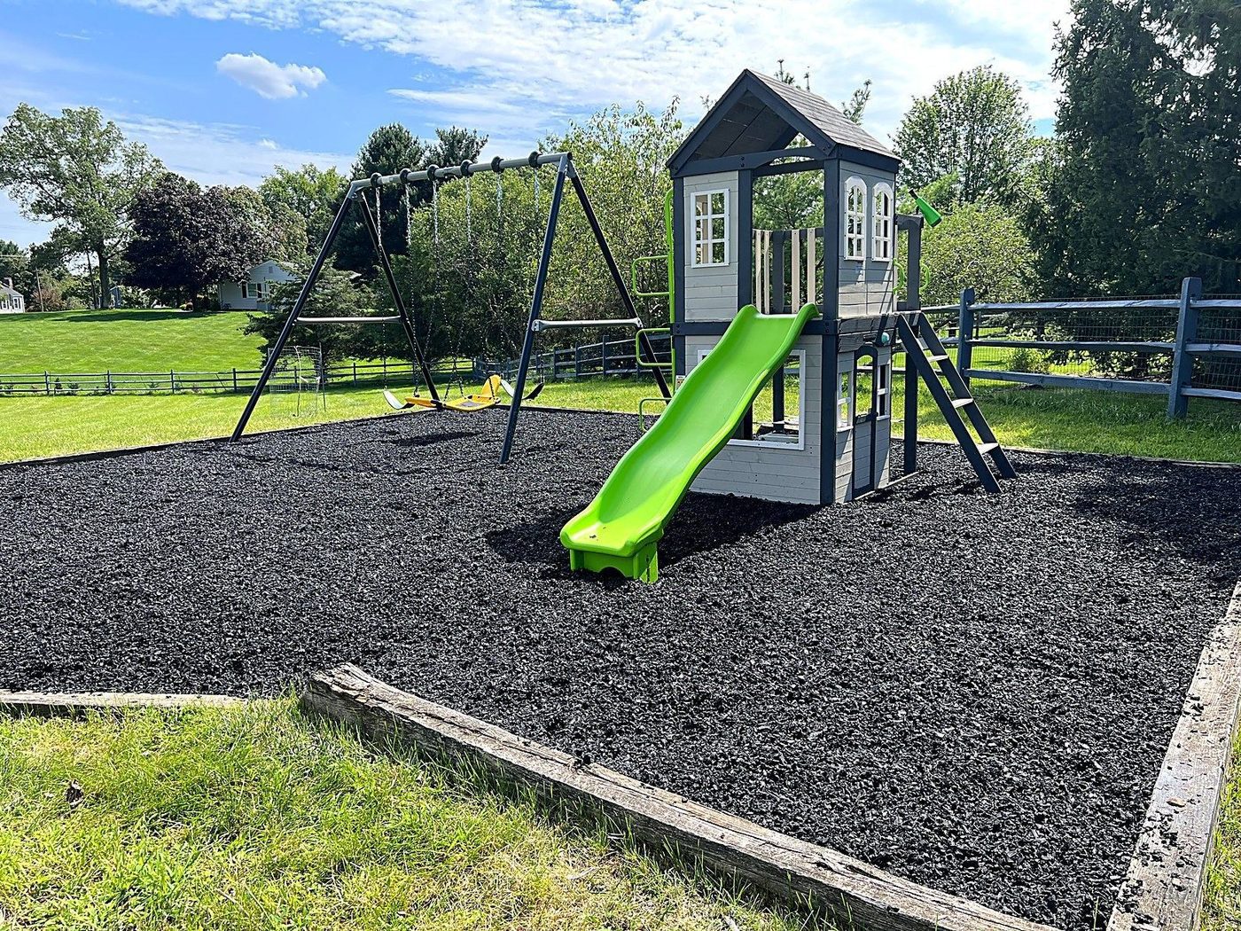 Backyard play structure with a slide on a rubber mulch bed