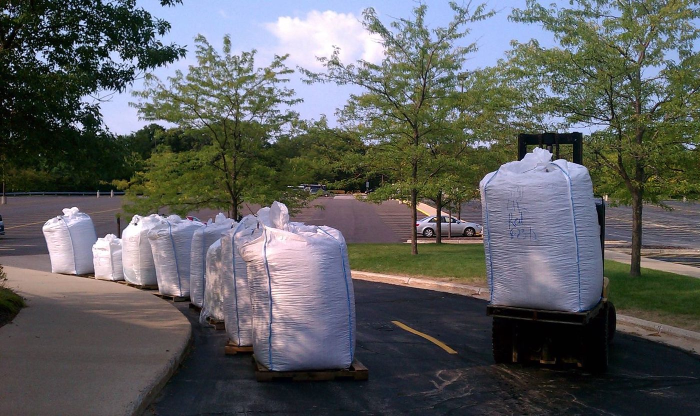 Super sacks of rubber mulch set out on pallets by a forklift during a commercial delivery
